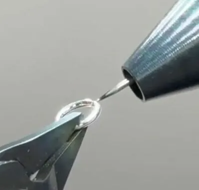 Close-up of a welder tip joining a link of permanent jewelry.